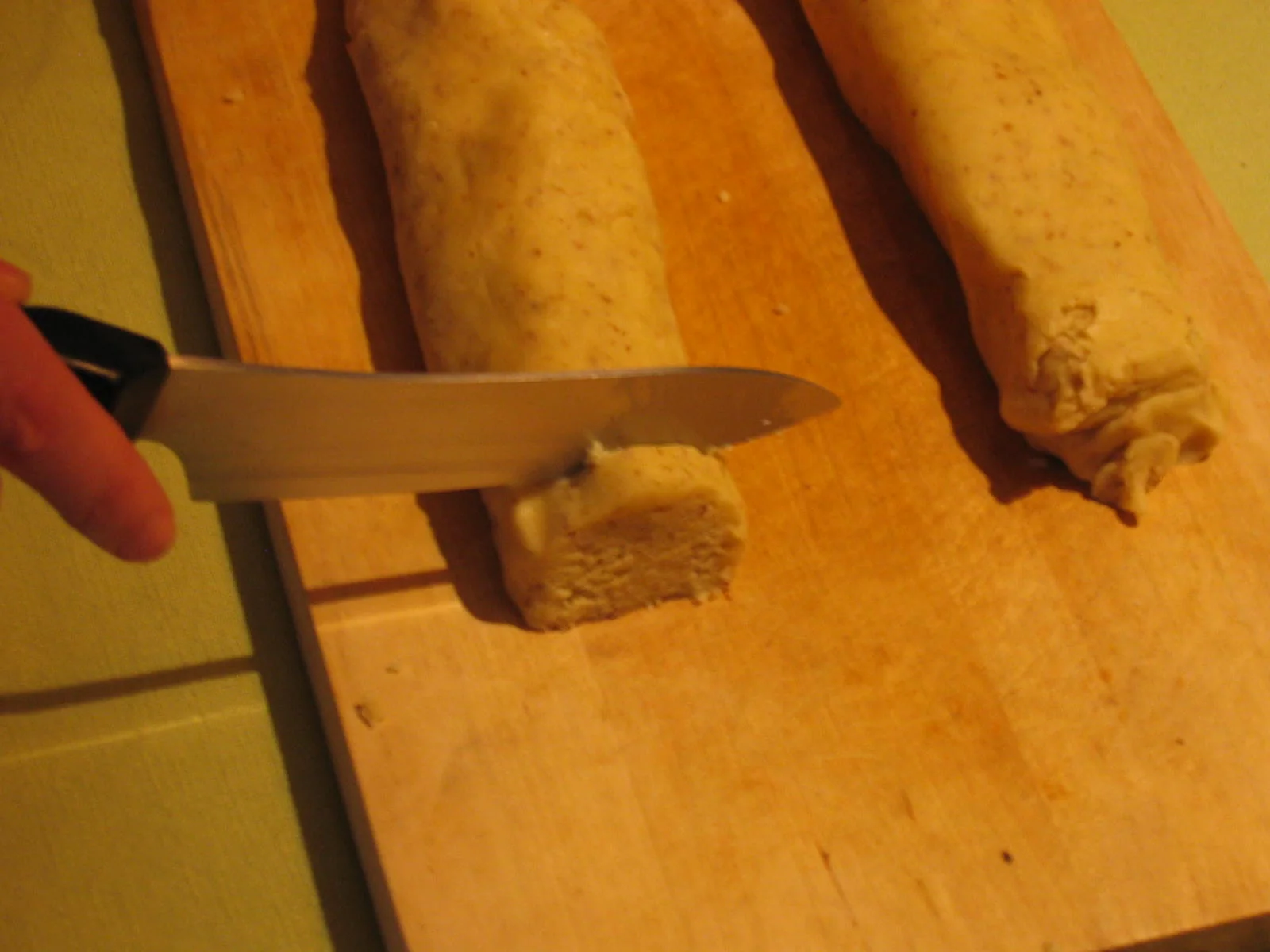 Eine Teigrolle wird in Portionen für Kipferl geschnitten.