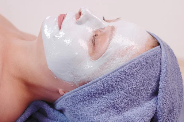 Person mit cremiger Gesichtsmaske und zurückgehaltenem Haar