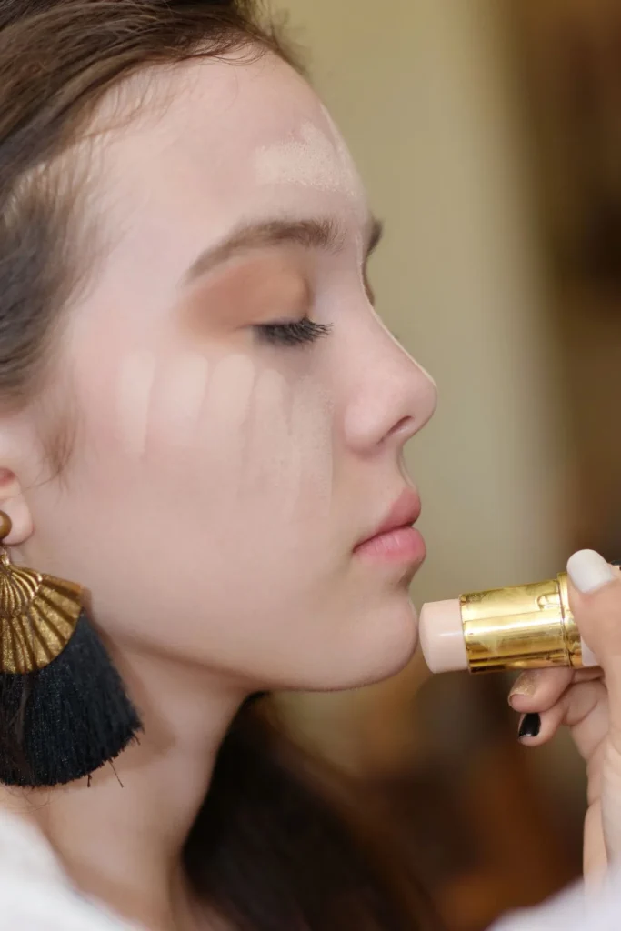 Helle Make-up-Striche auf Wange und Stirn vor dem Verblenden
