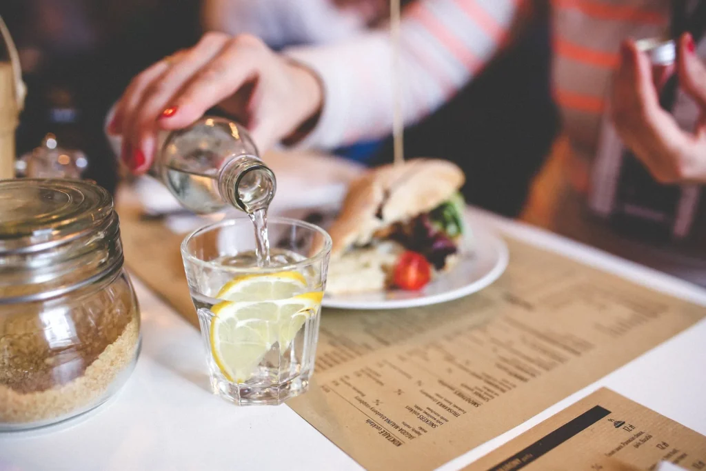 Eine Person gießt Wasser aus einem Krug in ein Glas