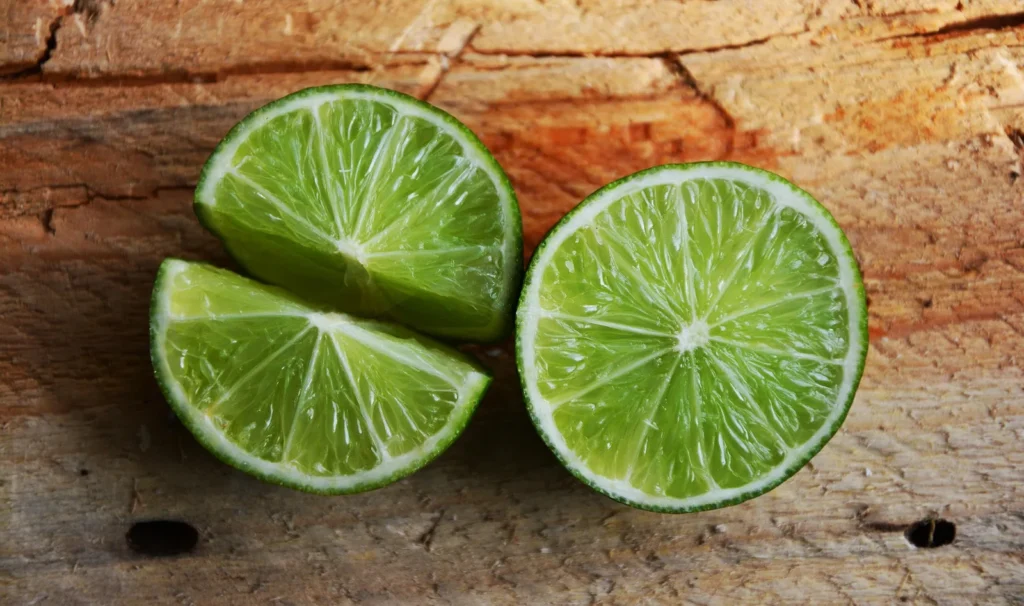 Halbierte und geviertelte Limetten auf Holz