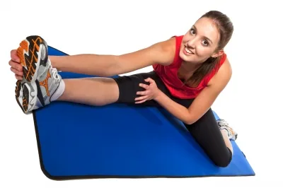 Frau dehnt die Beine auf einer Trainingsmatte